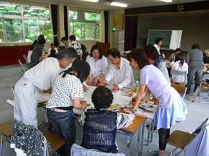 づくだせ会の方々と高甫地域の課題等について長机を並べ話し合う大学生たちの写真