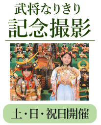 よろいかぶとを着た小学生の男の子と、お雛さまの衣装を羽織った小学生の女の子が、五月人形飾りの前で並んで写る写真