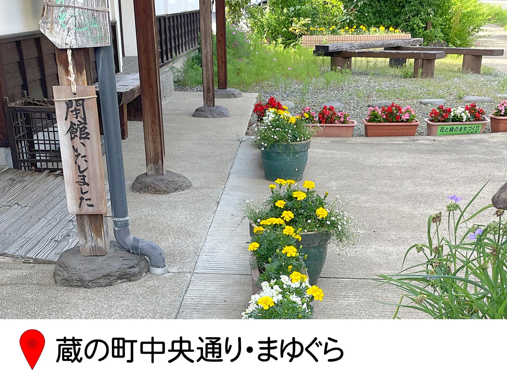 まゆぐらの入り口にプランターの花が並べられている写真