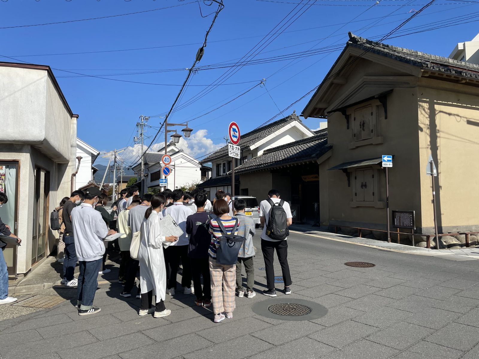 蔵が建つ建物の前で学生たちがメモをとっている様子の写真