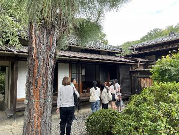 アートパーク内の歴史的建物園を見学し説明を聞く生徒たちの様子