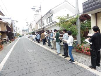 観光交流センター前の、蔵の通りで説明を聞く学生たち