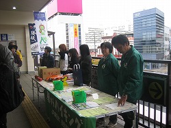 須坂駅前に長机を設置し、参加者6名がハイキングの出迎えをしている様子の写真