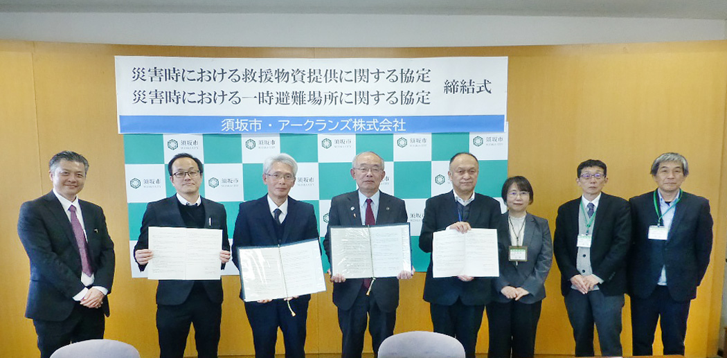 協定式の写真。協定書を持ち、三木市長を中心に、向かって左側にアークランズのみなさん、向かって右側に市役所諸君が並ぶ。