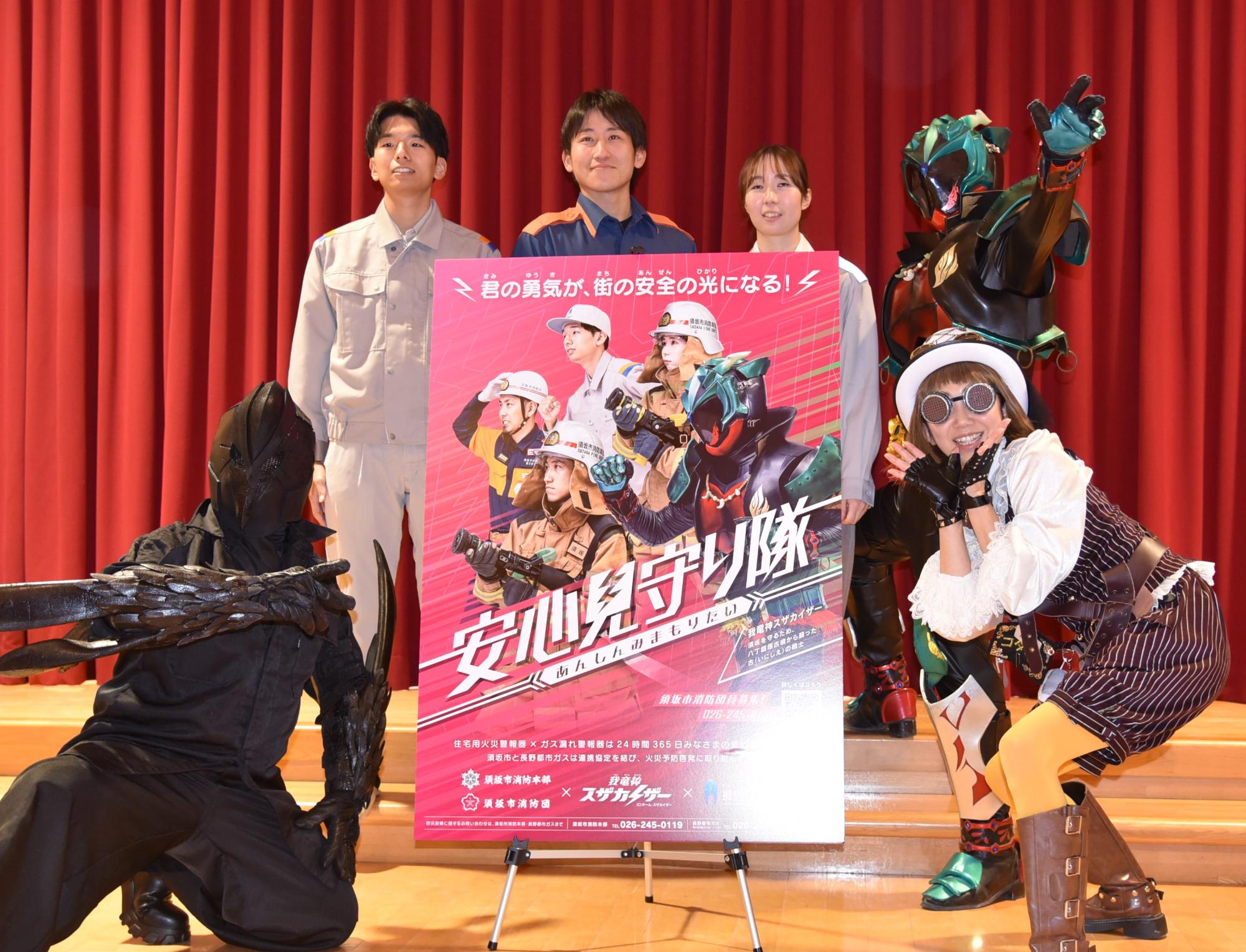 スザカイザーと仲間2人と消防士2人と長野都市ガス社員の6人が安心見守り隊のポスターを囲んで微笑んでポーズをとっている写真