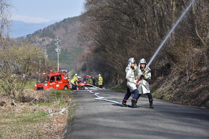 防火衣を着た消防団員2名が、山に向けて放水する訓練の様子を写した写真