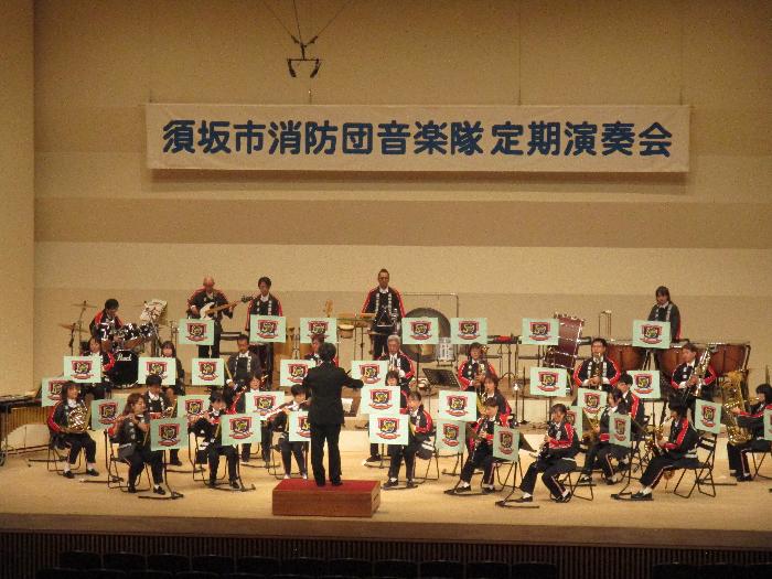 指揮者に合わせ演奏を行っている音楽隊の方々を写した写真