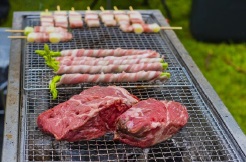 炭火のバーベキューコンロで肉や野菜を焼いている。