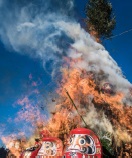 松飾やだるまが勢いのよい炎に包まれている。どんど焼き。