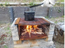 ブロック製の炉で飯ごうを焚いている。炉の中では薪が炎を上げている。