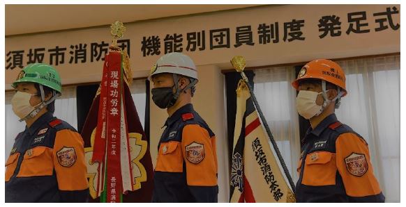 機能別団員制度発足式で緑、白、オレンジのヘルメットをかぶった団員3名を斜め横から上半身を写した写真