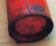 赤く塗られた表面の層が所々剥がれて黒く腐食している消火器の写真