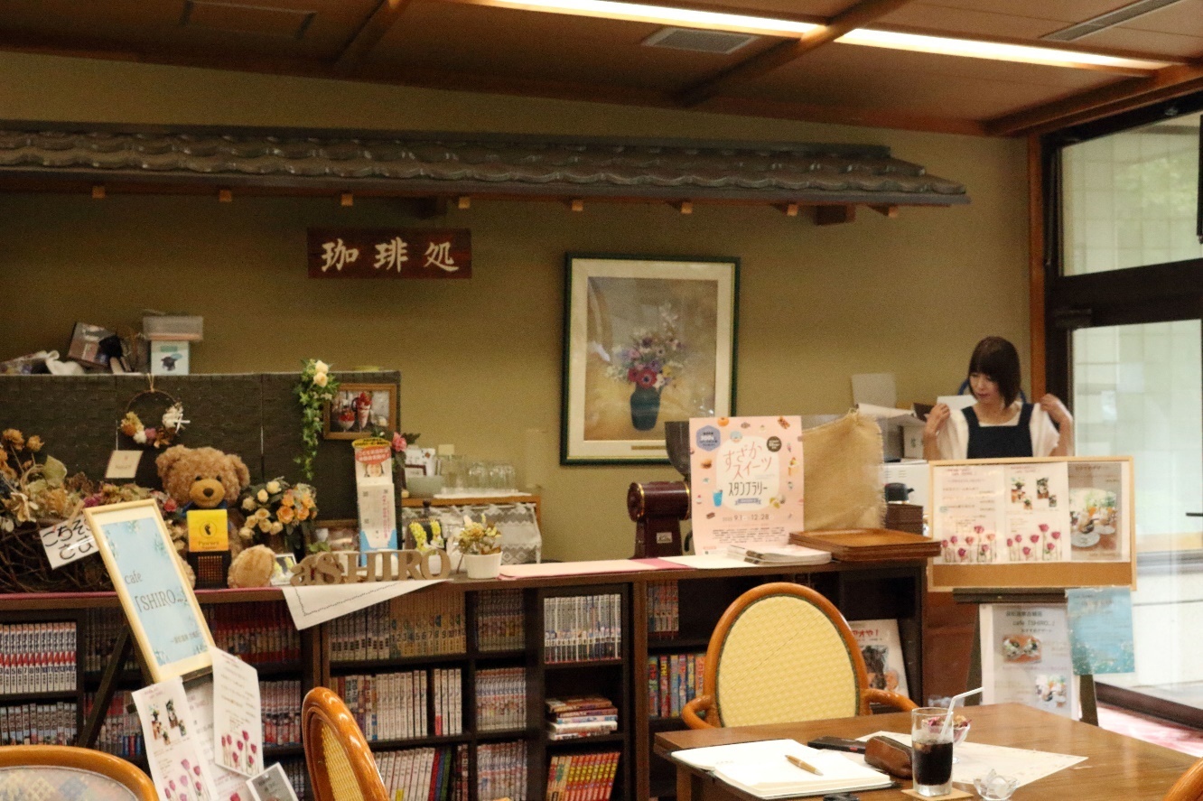 中央に置かれた木製の本棚にはたくさんの本が並んでおり、その前にはテーブルと椅子が置かれている店内の様子写真