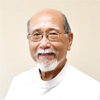 医師の写真。眼鏡をかけ、白いひげをたくわえた年配の男性医師が穏やかな笑顔を向けている。