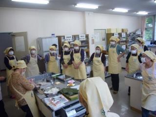 講師が料理をしている様子を大勢の人が見ている写真